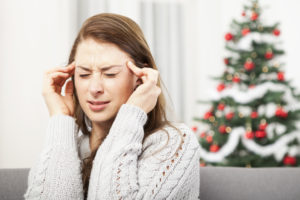 young unhappy girl has headache of christmas stress with tree in background